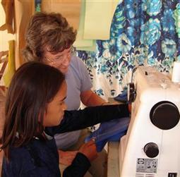 Child learning to use a sewing machine